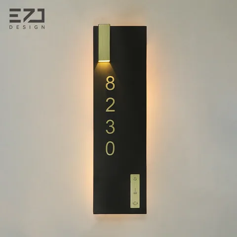 Black vertical hotel door sign with gold-colored accent light